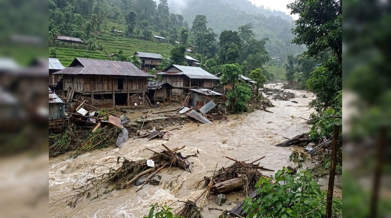 Muddy floodwaters and debris coursing past damaged structures in a hilly settlement in Arunachal Pradesh.