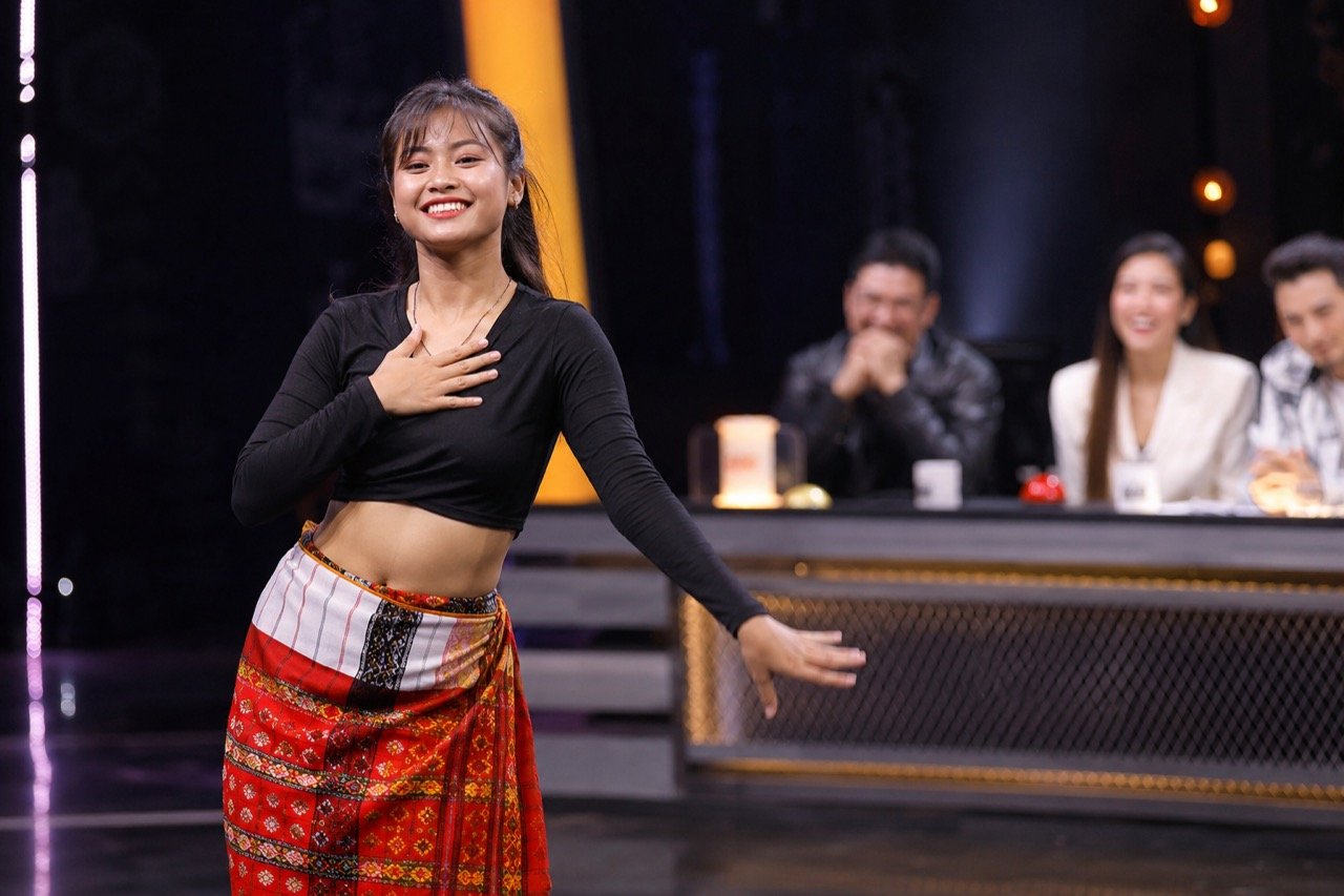 A young dancer performing under stage lights on a web-show set, with judges' silhouettes and phone screens capturing the viral moment