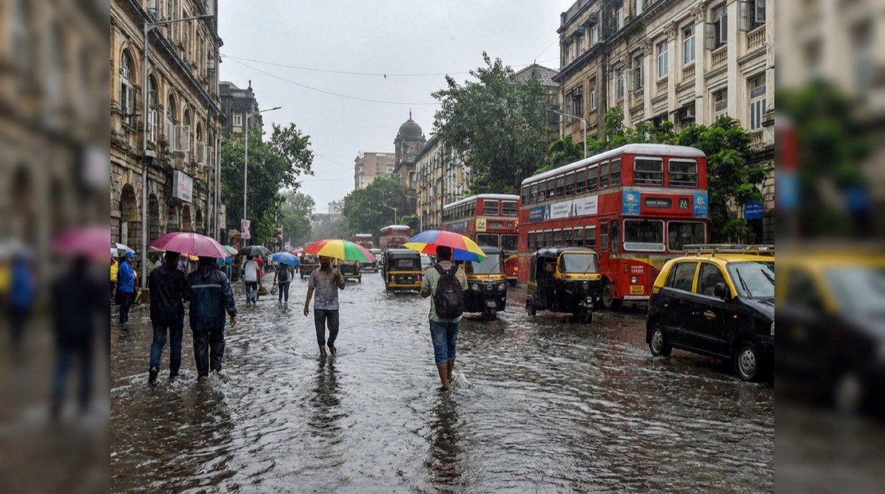 Commuters with umbrellas on a rain-soaked Mumbai street as the southwest monsoon advances into Maharashtra